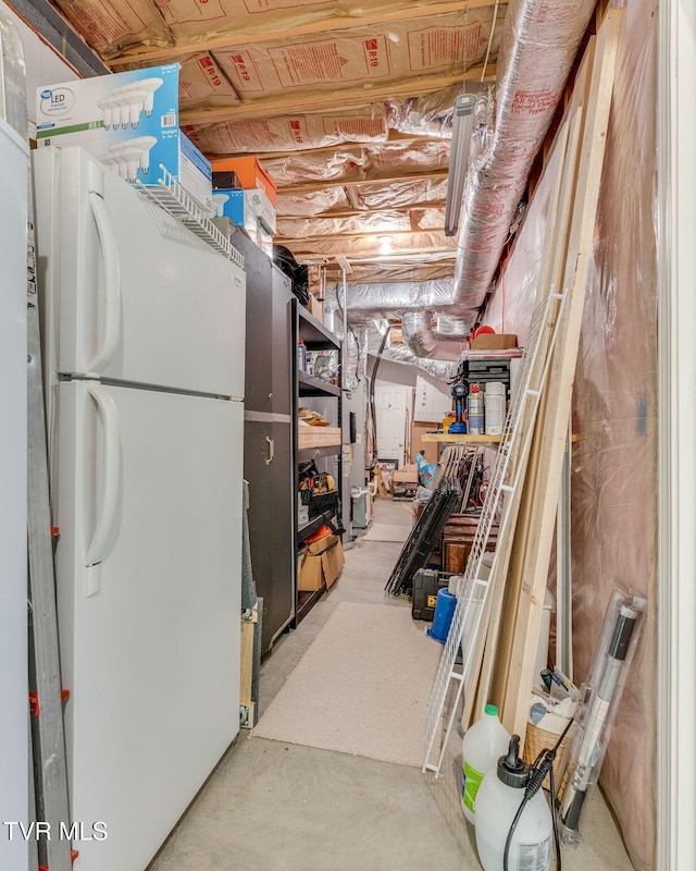 unfinished basement featuring freestanding refrigerator