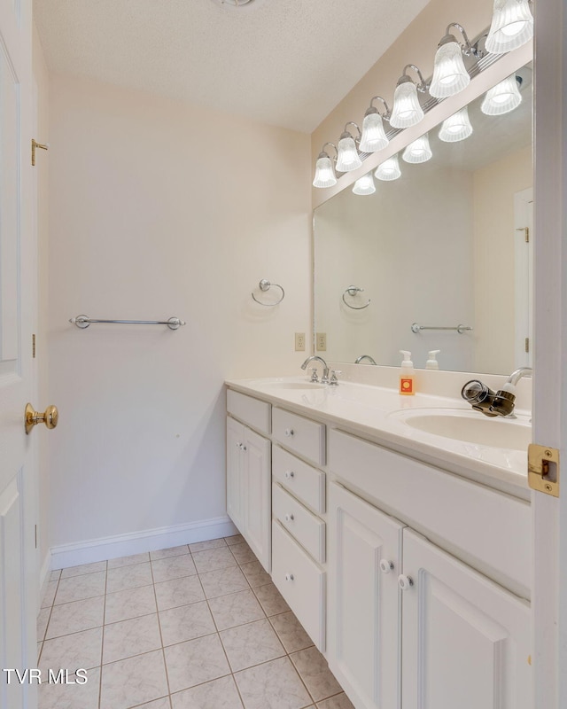 bathroom with double vanity, tile patterned flooring, baseboards, and a sink