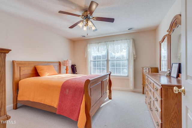 bedroom featuring visible vents, a ceiling fan, a textured ceiling, baseboards, and light colored carpet