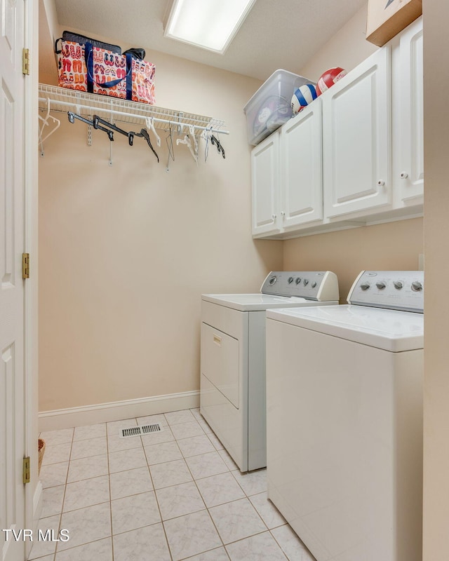 clothes washing area featuring light tile patterned floors, baseboards, cabinet space, and washing machine and dryer