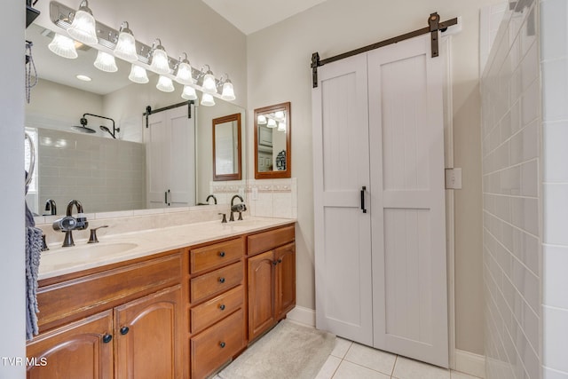 full bath with a sink, a tile shower, double vanity, and tile patterned flooring