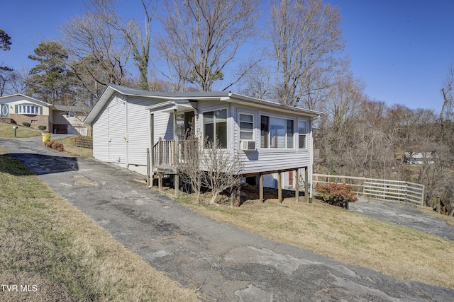 view of front facade featuring aphalt driveway, a front lawn, and fence