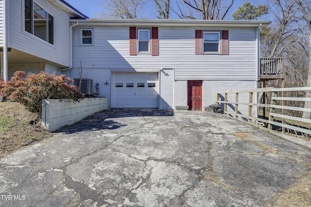 view of front of house featuring aphalt driveway, central AC, fence, and an attached garage