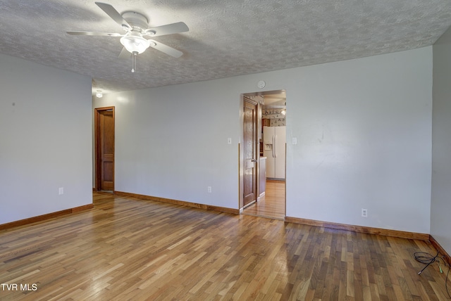 empty room featuring a textured ceiling, baseboards, and wood finished floors