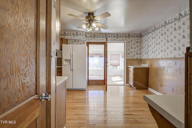 bathroom featuring a ceiling fan, wood finished floors, wainscoting, and wallpapered walls