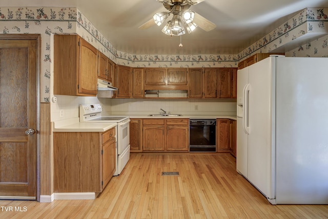 kitchen with under cabinet range hood, white appliances, a sink, light wood-type flooring, and wallpapered walls