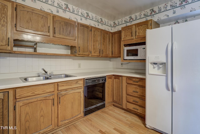 kitchen with white appliances, wallpapered walls, light countertops, light wood-type flooring, and a sink