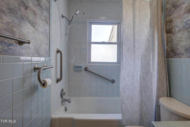 bathroom with shower / tub combo, wainscoting, toilet, and tile walls