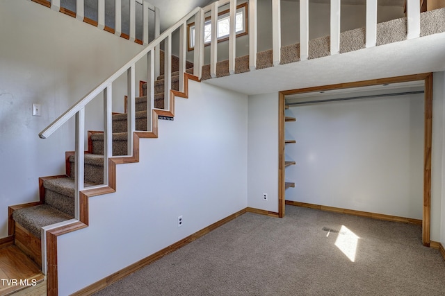 stairs with carpet, a towering ceiling, and baseboards