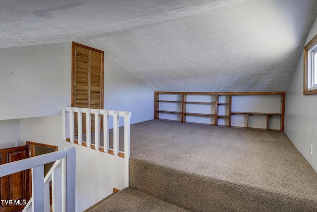 bonus room with lofted ceiling, a textured ceiling, and carpet flooring