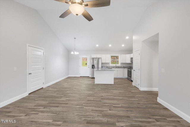 kitchen with white cabinets, dark wood finished floors, a kitchen island, open floor plan, and stainless steel appliances