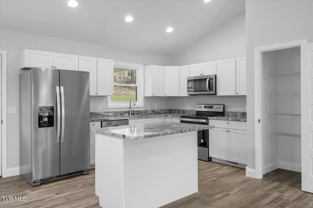 kitchen with appliances with stainless steel finishes, white cabinetry, and a kitchen island