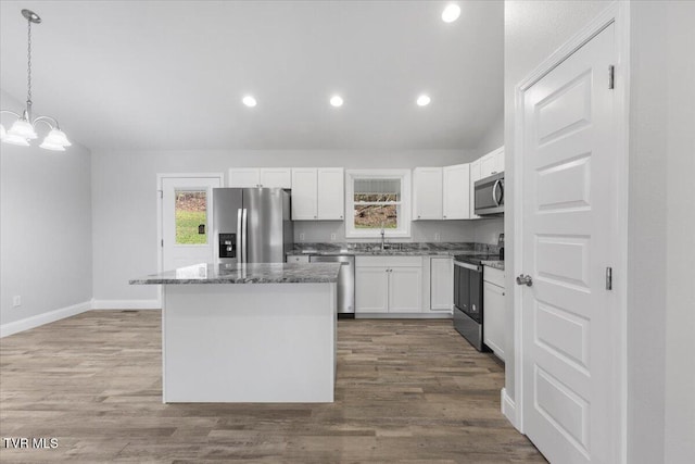 kitchen with a chandelier, wood finished floors, white cabinetry, appliances with stainless steel finishes, and a center island