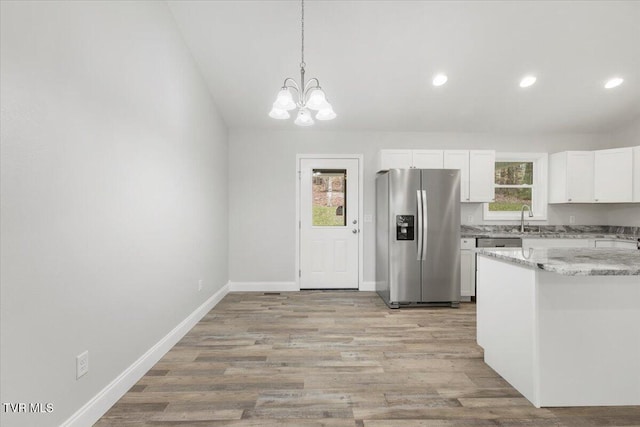 kitchen with a sink, light wood finished floors, stainless steel fridge, and a healthy amount of sunlight