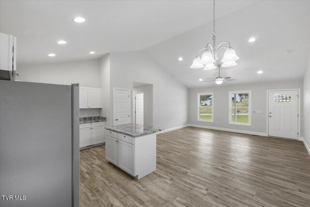 kitchen featuring wood finished floors, a center island, decorative light fixtures, freestanding refrigerator, and white cabinetry