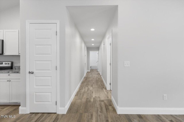 corridor with recessed lighting, wood finished floors, and baseboards