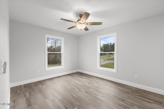 spare room with ceiling fan, wood finished floors, and baseboards