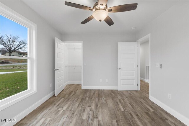 unfurnished bedroom featuring visible vents, multiple windows, baseboards, and wood finished floors