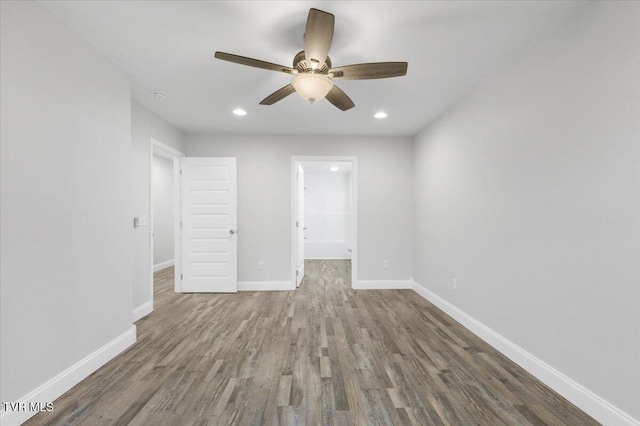 unfurnished bedroom with baseboards, a ceiling fan, wood finished floors, a walk in closet, and recessed lighting