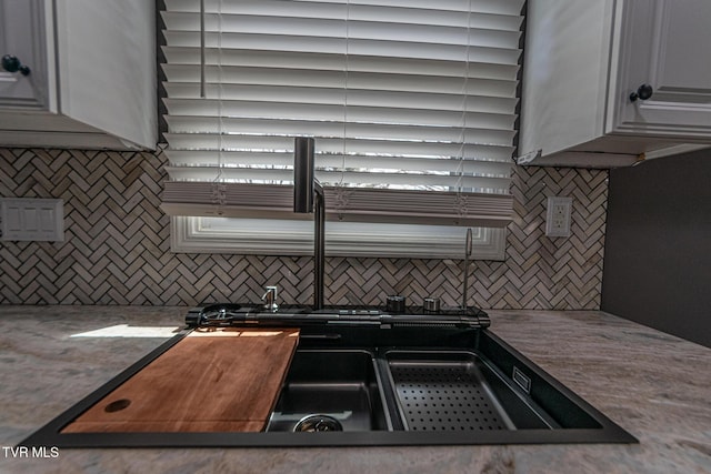 kitchen featuring tasteful backsplash and white cabinetry