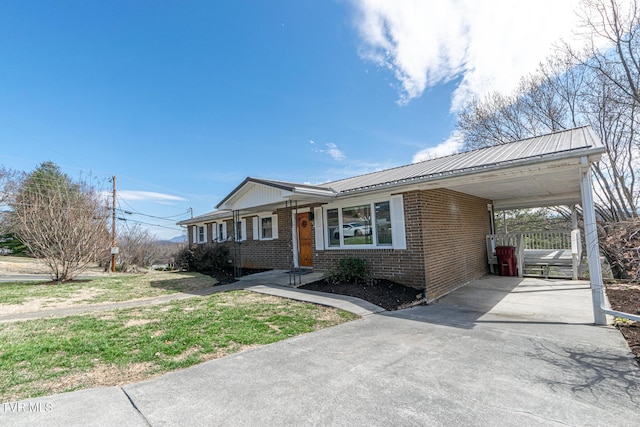 view of front of house with metal roof, a carport, brick siding, and concrete driveway