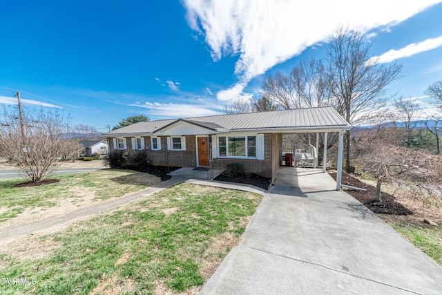 ranch-style house with metal roof, an attached carport, brick siding, driveway, and a front lawn