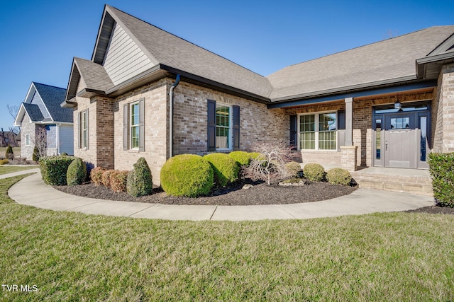 exterior space with a yard, brick siding, and roof with shingles