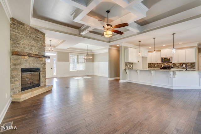 unfurnished living room with a wainscoted wall, crown molding, a fireplace, and dark wood-type flooring