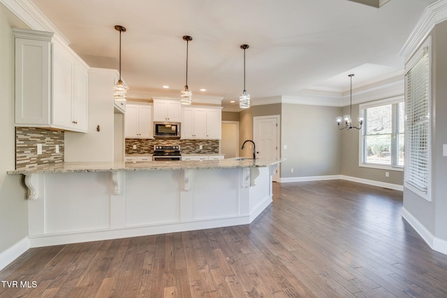 kitchen featuring dark wood finished floors, white cabinets, appliances with stainless steel finishes, a peninsula, and backsplash