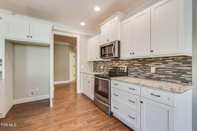 kitchen featuring stainless steel appliances, white cabinets, and backsplash