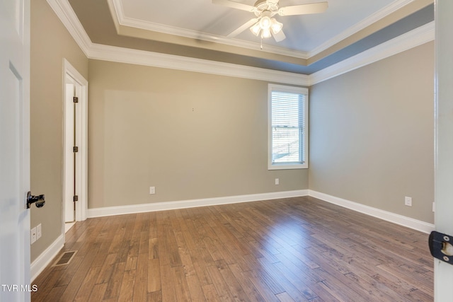 empty room featuring a raised ceiling, visible vents, and wood finished floors