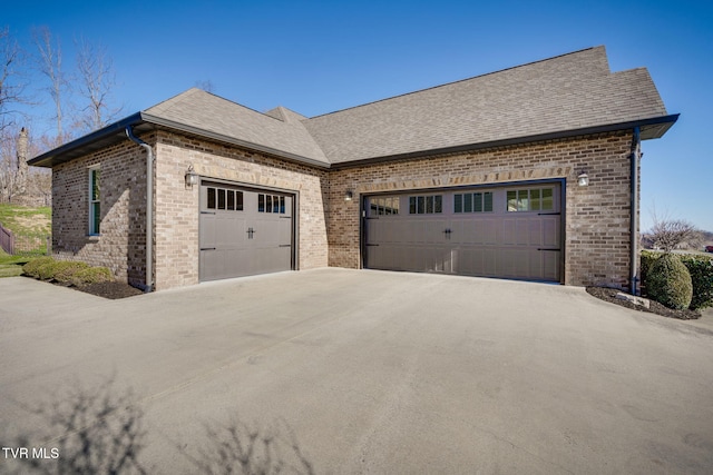 view of side of property featuring a garage, concrete driveway, and brick siding