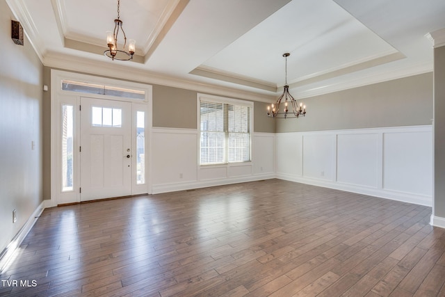 entryway with dark wood-style floors, a tray ceiling, crown molding, and an inviting chandelier