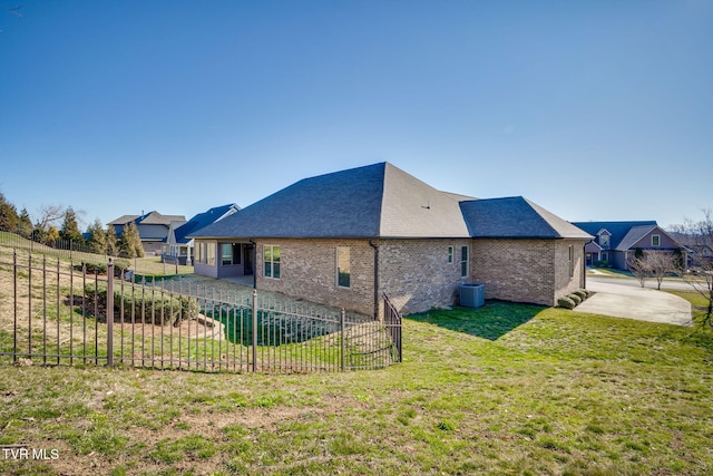 back of property featuring central AC unit, brick siding, fence, a yard, and a patio area