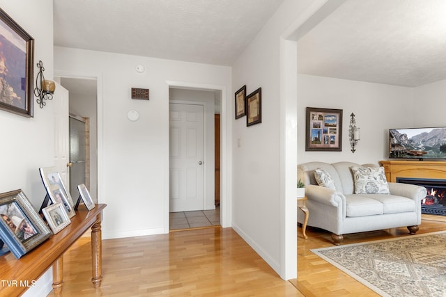 interior space featuring light wood finished floors, a textured ceiling, and baseboards