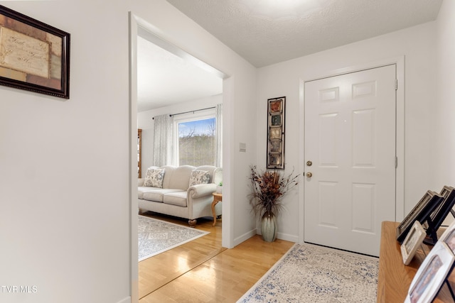 entrance foyer featuring a textured ceiling, light wood-type flooring, and baseboards