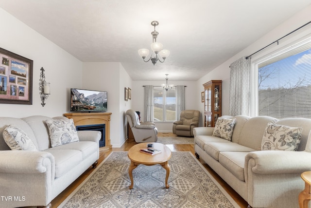 living area with a fireplace, wood finished floors, baseboards, and a chandelier