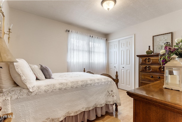 bedroom featuring a closet, a textured ceiling, and light wood finished floors