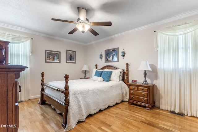 bedroom featuring visible vents, light wood-style floors, and crown molding