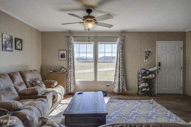 living room featuring ceiling fan, a textured ceiling, crown molding, and wood finished floors