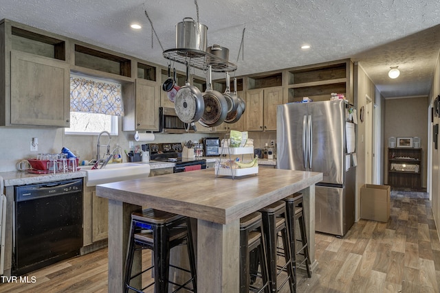 kitchen with butcher block countertops, stainless steel appliances, light wood-type flooring, open shelves, and a sink