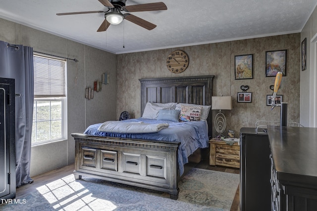 bedroom featuring ceiling fan, a textured ceiling, ornamental molding, and wood finished floors