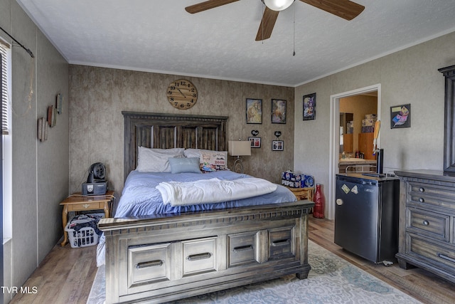 bedroom featuring ceiling fan, ornamental molding, a textured ceiling, and wood finished floors