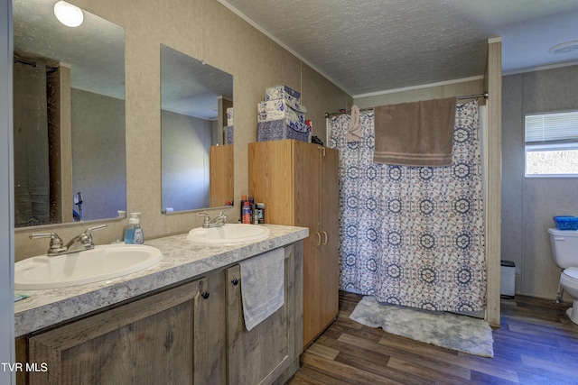 full bathroom with toilet, a textured ceiling, a sink, and wood finished floors