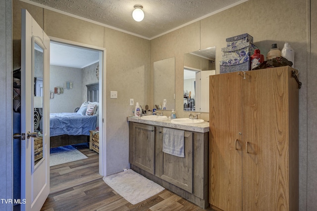 ensuite bathroom with connected bathroom, ornamental molding, a sink, and wood finished floors