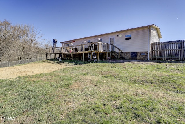 back of house with a deck, a lawn, and fence