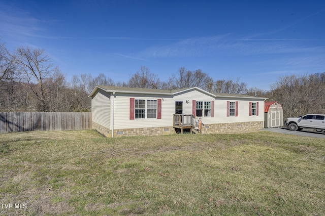 manufactured / mobile home featuring crawl space, fence, an outdoor structure, a shed, and a front lawn