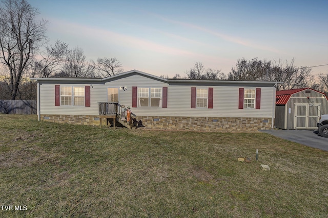 manufactured / mobile home featuring a storage unit, a lawn, and an outdoor structure