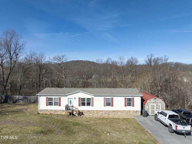 view of front facade with a storage unit, fence, a view of trees, and a front yard