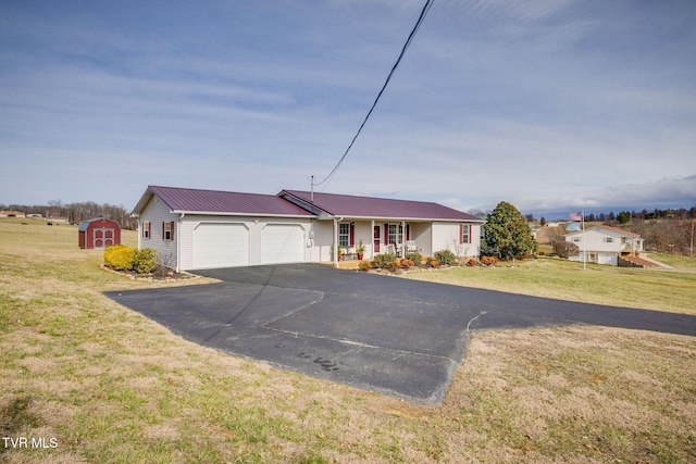 ranch-style house featuring a garage, a storage shed, aphalt driveway, and a front yard